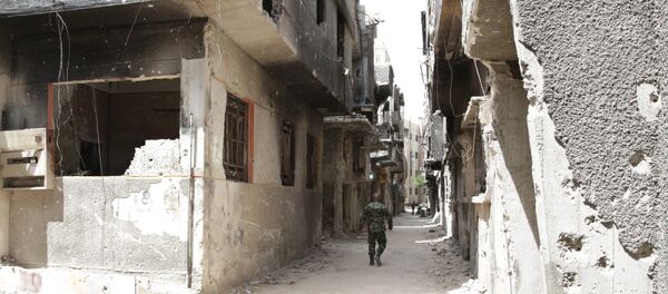 FILE PHOTO. A soldier walks down an alley through heavy damage during a government escorted visit to Yarmouk refugee camp in Damascus, Syria, Thursday, April 9, 2015 - Sputnik International