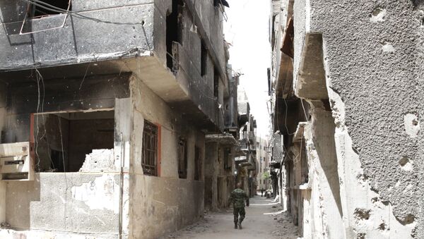 FILE PHOTO. A soldier walks down an alley through heavy damage during a government escorted visit to Yarmouk refugee camp in Damascus, Syria, Thursday, April 9, 2015 - Sputnik International