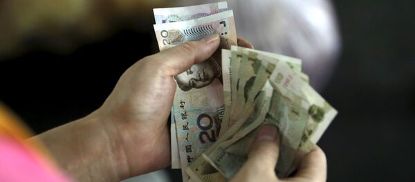 A customer counts Chinese Yuan notes at a market in Beijing, August 12, 2015 A customer counts Chinese Yuan notes at a market in Beijing, August 12, 2015 - Sputnik International