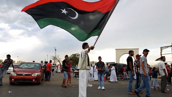 A Libyan man waves his national flag during a demonstration against supporters of the regime of former dictator Moamer Kadhafi in the eastern city of Benghazi on August 7, 2015. - Sputnik International