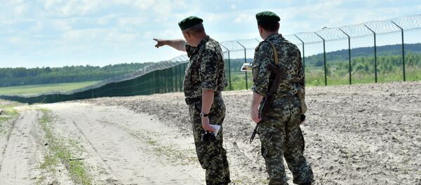 Ukrainian border guards patrol on July 2, 2015 along the barbed wire fence on the Senkivka border post, around 200 kilometres (125 miles) north of the Ukrainian capital Kiev. Ukrainian border guards patrol on July 2, 2015 along the barbed wire fence on the Senkivka border post, around 200 kilometres (125 miles) north of the Ukrainian capital Kiev. - Sputnik International