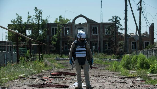 An OSCE monitor checks the territory for mines during a patrol in Shyrokyne, Donetsk region eastern Ukraine, Saturday, July 4, 2015 - Sputnik International