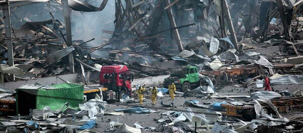 Rescue workers wearing chemical protective suits walk at the site of the explosions at the Binhai new district in Tianjin, China, August 14, 2015 Rescue workers wearing chemical protective suits walk at the site of the explosions at the Binhai new district in Tianjin, China, August 14, 2015 - Sputnik International