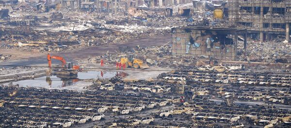Rescuers walk next to damaged vehicles at the site of Wednesday night's explosions in Binhai new district of Tianjin, China, August 15, 2015 Rescuers walk next to damaged vehicles at the site of Wednesday night's explosions in Binhai new district of Tianjin, China, August 15, 2015 - Sputnik International