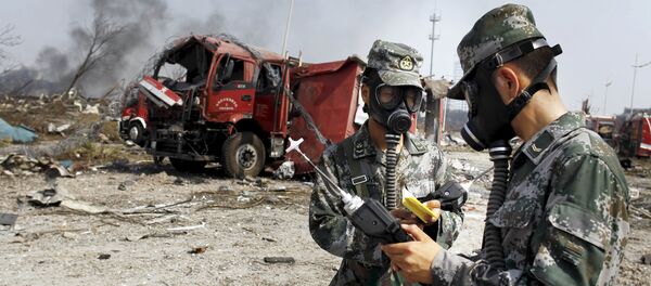 Soldiers of the People's Liberation Army anti-chemical warfare corps work next to a damaged firefighting vehicle at the site of Wednesday night's explosions at Binhai new district in Tianjin, China Soldiers of the People's Liberation Army anti-chemical warfare corps work next to a damaged firefighting vehicle at the site of Wednesday night's explosions at Binhai new district in Tianjin, China - Sputnik International