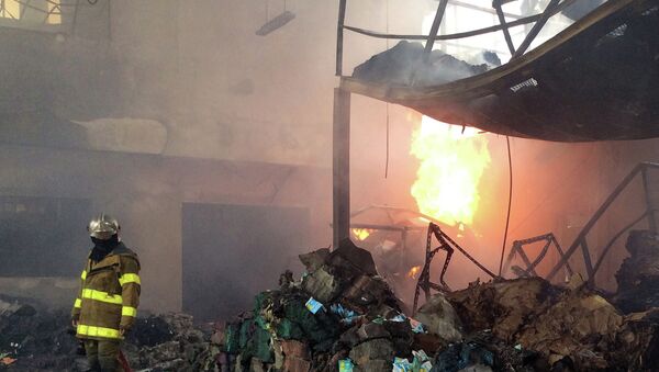 A Thai fireman (L) stands inside a scrap metal warehouse after an explosion - Sputnik International