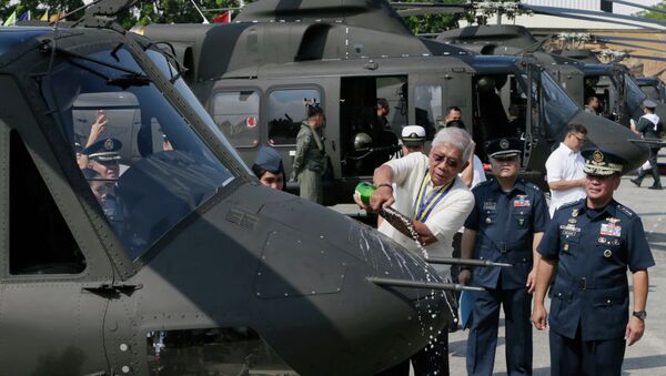 Philippine National Defense Chief Voltaire Gazmin pours champagne on a Bell-412EP helicopter. - Sputnik International