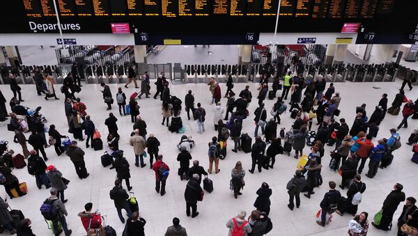People wait with their luggage by the departure boards in Waterloo train station in central London - Sputnik International