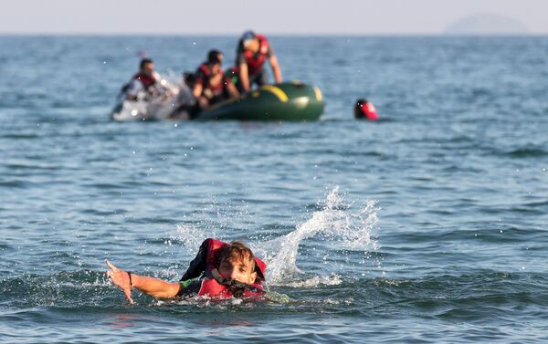 Migrants and refugees, one of them swims, arrive after crossing from Turkey, at the southeastern island of Kos, Greece, Monday, Aug. 17, 2015 - Sputnik International