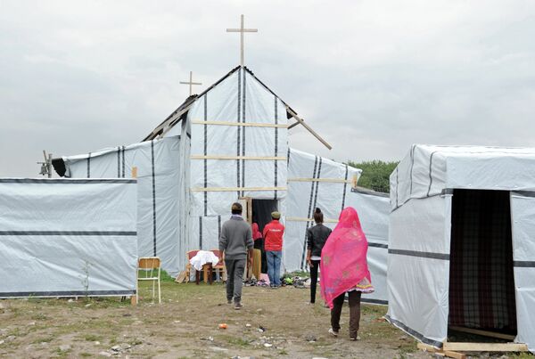Migrants enter into the makeshift church built in the migrant camp called the 'new jungle' in Calais to attend a mass. Waiting for the perfect opportunity to cross over, many of the some 3,000 migrants in the Calais area stay in the 'New Jungle', a makeshift camp several kilometres from the city center. - Sputnik International