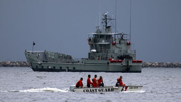 Members of the Philippine coast guard on a motorboat drive past one of the two decommissioned Landing Craft Heavy (LCH) vessels donated by the Australian government to the Philippines, docked at a bay in Manila August 9, 2015 - Sputnik International
