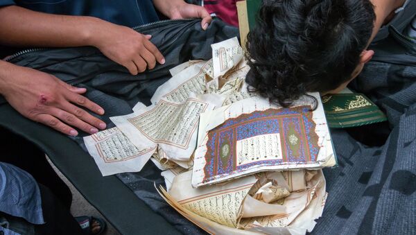 Refugees bow over ripped out pages from a Koran in a first registration center for refugees in Suhl, eastern Germany, on August 20, 2015 - Sputnik International