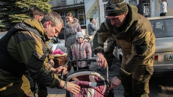 Militia of the Angel volunteer peacekeeping unit from the Donetsk and Luhansk People's Republics evacuate a woman and a child from the city of khartsyzsk - Sputnik International