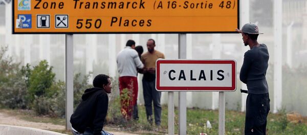 Migrants stand near a city sign along a road near the makeshift camp called The New Jungle in Calais, France, August 19, 2015 Migrants stand near a city sign along a road near the makeshift camp called The New Jungle in Calais, France, August 19, 2015 - Sputnik International
