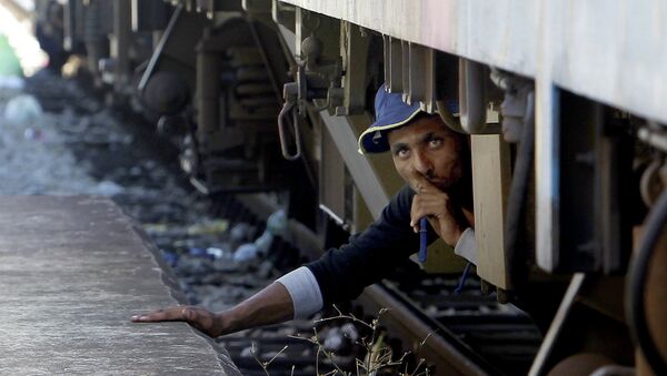 A migrant, hiding under a train, tries to sneak on a train towards Serbia, at the railway station in the southern Macedonian town of Gevgelija, on Monday, Aug. 17, 2015 - Sputnik International