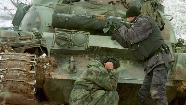 A Yugoslav special forces policeman shoots his rifle at opposing Kosovo Liberation Army forces as a Yugoslav Army tank driver covers his ears after coming under fire Tuesday Feb. 23, 1999 in the village of Bukos - Sputnik International