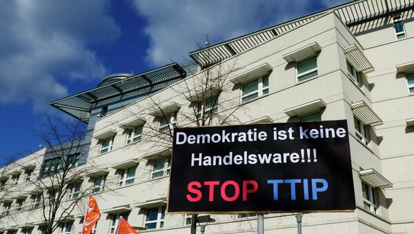 A sign reading Democracy is no trading good, Stop TTIP is lifted in front of the US embassy during a protest against the proposed US-EU free trade pact or Transatlantic Trade and Investment Partnership (TTIP) in Berlin on April 18, 2015 - Sputnik International