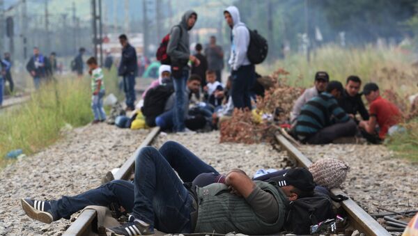 Migrants rest while waiting to pass the Greek-Macedonian border, guarded by Macedonian police near the town of Idomeni, northern Greece, on August 21, 2015 - Sputnik International