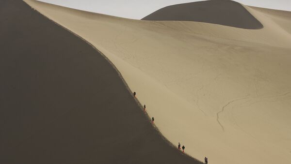 Tourists ride camels on the edge of the desert that threatens to engulf the ancient Chinese city of Dunhuang in China's northwest Gansu province. (File) - Sputnik International