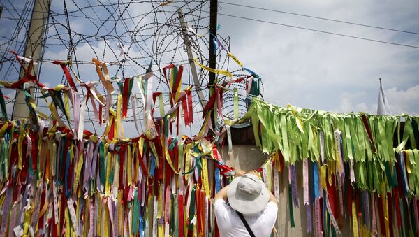 A tourist hangs a ribbon bearing messages wishing the unification of the two Koreas on a barbed-wire fence at the Imjingak pavilion near the demilitarized zone separating the two Koreas in Paju, South Korea - Sputnik International
