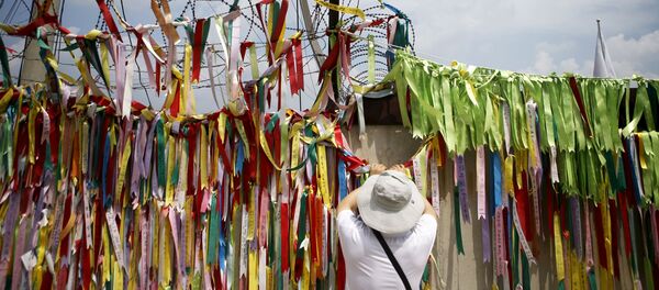 A tourist hangs a ribbon bearing messages wishing the unification of the two Koreas on a barbed-wire fence at the Imjingak pavilion near the demilitarized zone separating the two Koreas in Paju, South Korea A tourist hangs a ribbon bearing messages wishing the unification of the two Koreas on a barbed-wire fence at the Imjingak pavilion near the demilitarized zone separating the two Koreas in Paju, South Korea - Sputnik International