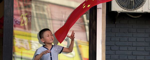 A child plays with a Chinese national flag near an area cordoned off for rehearsals ahead of a military parade to commemorate the end of World War II in Beijing, Saturday, Aug. 22, 2015 - Sputnik International