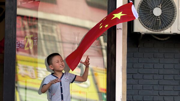 A child plays with a Chinese national flag near an area cordoned off for rehearsals ahead of a military parade to commemorate the end of World War II in Beijing, Saturday, Aug. 22, 2015 - Sputnik International