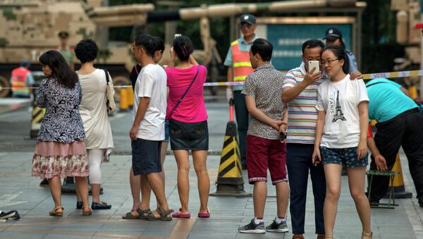 Chinese residents gather to watch a Chinese self propelled howitzer lined up for rehearsals ahead of the Sept. 3 military parade to commemorate the end of World War II in Beijing, Saturday, Aug. 22, 2015 - Sputnik International