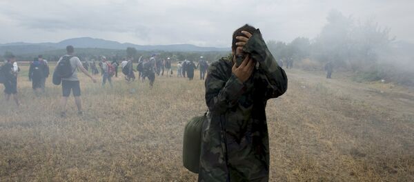 A migrant covers his face to avoid inhaling tear gas while others flee, as Macedonian police special forces block them from entering Macedonia on Greece's, near the village of Idomeni, Greece, August 22, 2015. A migrant covers his face to avoid inhaling tear gas while others flee, as Macedonian police special forces block them from entering Macedonia on Greece's, near the village of Idomeni, Greece, August 22, 2015. - Sputnik International
