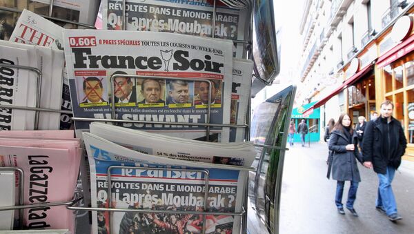 People are seen walking behind French daily newspapers displayed at a news kiosk in Paris. (File) - Sputnik International