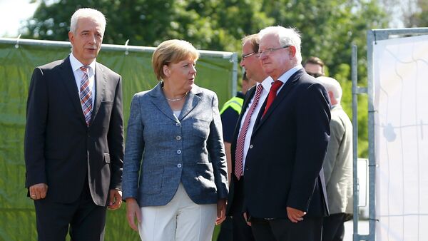 Saxony State Prime Minister Stanislaw Tillich, German Chancellor Angela Merkel, major Juergen Opitz and President of the German Red Cross Rudolf Seiters (LtoR) arrive to visit an asylum seekers accomodation facility in the eastern German town of Heidenau near Dresden, August 26, 2015 where last week more than 30 police were injured in clashes, when a mob of several hundred people pelted officers with bottles and fireworks - Sputnik International