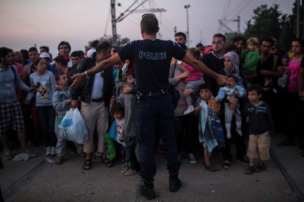 A Greek police officer gives orders to Syrian refugees as they wait to cross the border from Greece to Macedonia, in the border town of Idomeni , northern Greece, on Wednesday, Aug. 26, 2015 - Sputnik International
