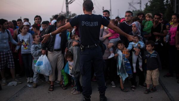 A Greek police officer gives orders to Syrian refugees as they wait to cross the border from Greece to Macedonia, in the border town of Idomeni , northern Greece, on Wednesday, Aug. 26, 2015 - Sputnik International