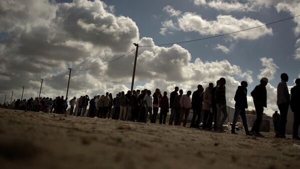 Migrants line up as the wait for a food ration distributed by the Banque Alimentaire of Calais at a camp in northern France, Tuesday, Aug. 4, 2015 - Sputnik International