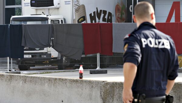 A police officer walks by a truck discovered abandoned on an Austrian motorway containing more than 70 bodies as it sits at a customs building with refrigeration facilities in the village of Nickelsdorf, Austria, August 28, 2015 - Sputnik International