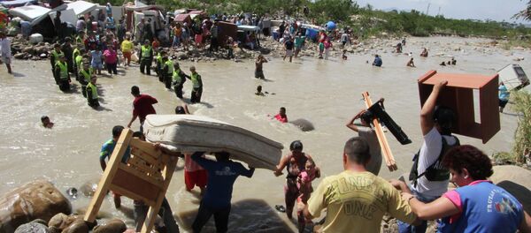 People carry their household belongings across the Tachira River from Venezuela, foreground, to Colombia, near San Antonio del Tachira, Venezuela, Tuesday, Aug. 25, 2015, during a mass exodus of Colombians living on the Venezuelan side of the border People carry their household belongings across the Tachira River from Venezuela, foreground, to Colombia, near San Antonio del Tachira, Venezuela, Tuesday, Aug. 25, 2015, during a mass exodus of Colombians living on the Venezuelan side of the border - Sputnik International