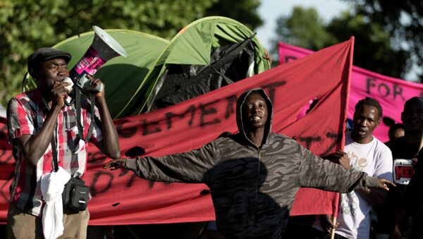 Migrants shout slogans and hold banners as they take part in a demonstration near the City of Fashion and Design (Cite de la mode et du design) on the Quai d'Austerlitz in Paris on August 5, 2015 - Sputnik International