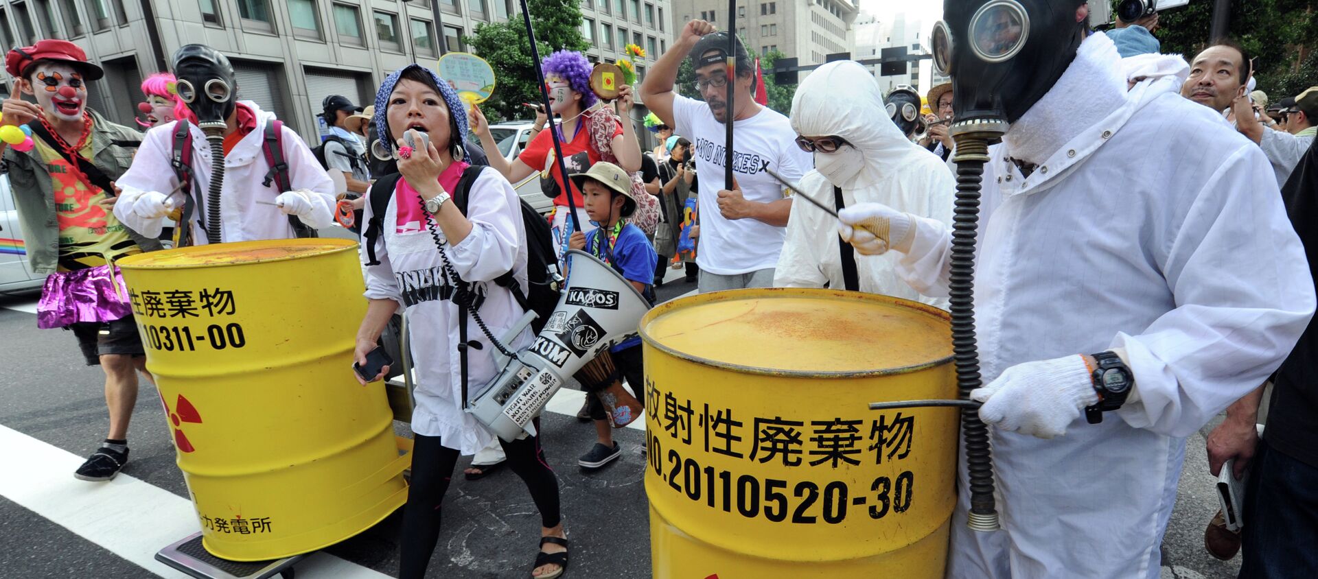 Protesters wearing gas masks and white costumes similar to those of decontamination workers at the crippled Fukushima plant beat drums painted with radioactive waste symbols during an anti nuclear power demonstration march in Tokyo on July 29, 2012 - Sputnik International, 1920, 07.06.2017