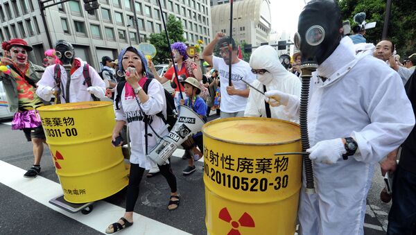 Protesters wearing gas masks and white costumes similar to those of decontamination workers at the crippled Fukushima plant beat drums painted with radioactive waste symbols during an anti nuclear power demonstration march in Tokyo on July 29, 2012 - Sputnik International