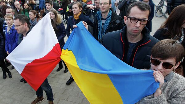 People holding a Poland flag, left, and a Ukraine flag listen to speakers during a demonstration in Warsaw, Poland showing their support for protesters in Ukraine - Sputnik International