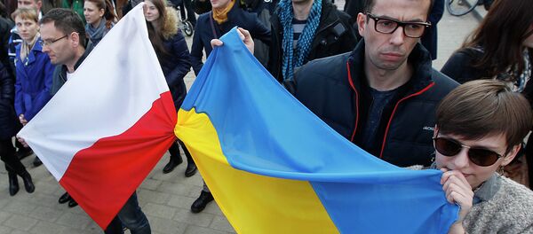People holding a Poland flag, left, and a Ukraine flag listen to speakers during a demonstration in Warsaw, Poland showing their support for protesters in Ukraine - Sputnik International