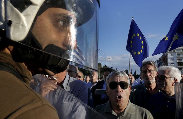 Riot police stand between anti-austerity and pro-EU protesters in front of the parliament building during a rally calling on the government to clinch a deal with its international creditors and secure Greece's future in the eurozone in Athens, Greece, in this June 22, 2015 file photo Riot police stand between anti-austerity and pro-EU protesters in front of the parliament building during a rally calling on the government to clinch a deal with its international creditors and secure Greece's future in the eurozone in Athens, Greece, in this June 22, 2015 file photo - Sputnik International
