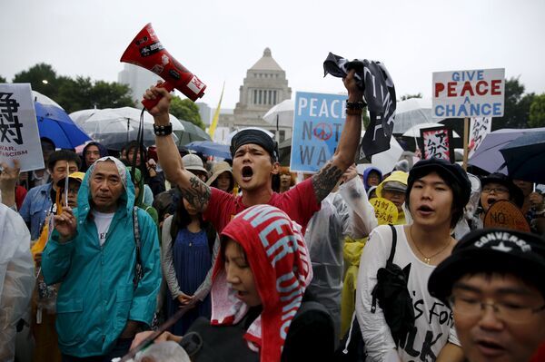 People hold placards and shout slogans as they protest against Japan's Prime Minister Shinzo Abe's security bill outside the parliament in Tokyo People hold placards and shout slogans as they protest against Japan's Prime Minister Shinzo Abe's security bill outside the parliament in Tokyo - Sputnik International
