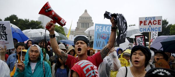 People hold placards and shout slogans as they protest against Japan's Prime Minister Shinzo Abe's security bill outside the parliament in Tokyo People hold placards and shout slogans as they protest against Japan's Prime Minister Shinzo Abe's security bill outside the parliament in Tokyo - Sputnik International