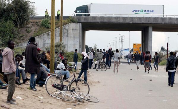 Migrants stand near a highway overpass near the makeshift camp called The New Jungle in Calais, France. Migrants stand near a highway overpass near the makeshift camp called The New Jungle in Calais, France. - Sputnik International