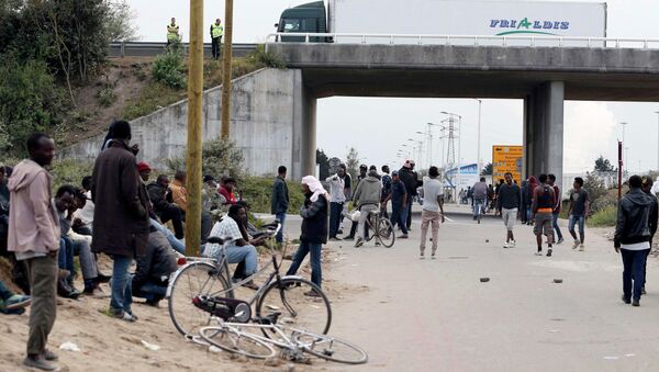 Migrants stand near a highway overpass near the makeshift camp called The New Jungle in Calais, France. - Sputnik International
