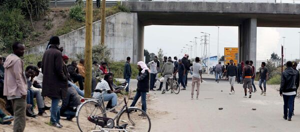 Migrants stand near a highway overpass near the makeshift camp called The New Jungle in Calais, France. Migrants stand near a highway overpass near the makeshift camp called The New Jungle in Calais, France. - Sputnik International