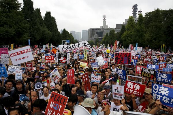 People hold placards and shout slogans as they protest against Japan's Prime Minister Shinzo Abe's security bill outside parliament in Tokyo People hold placards and shout slogans as they protest against Japan's Prime Minister Shinzo Abe's security bill outside parliament in Tokyo - Sputnik International