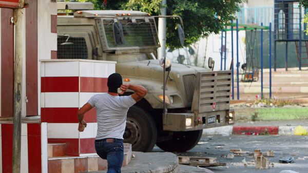 A Palestinian throws a stone toward an Israeli vehicle during clashes with Palestinians in an early morning operation in the West Bank city of Jenin, Wednesday, July 2, 2014. - Sputnik International