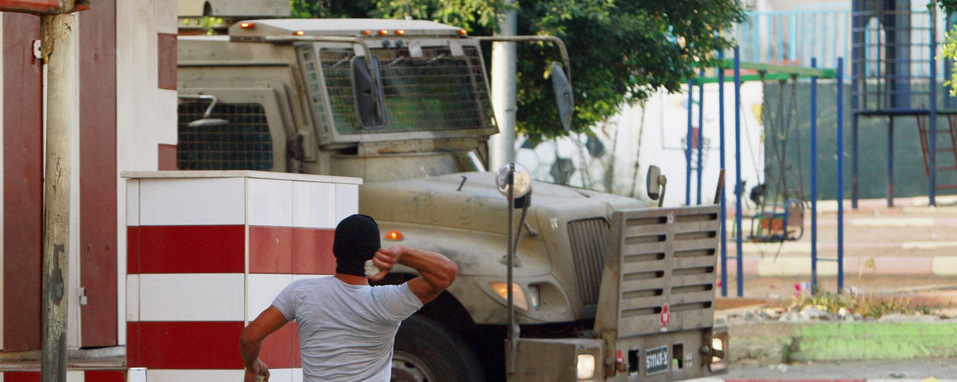 A Palestinian throws a stone toward an Israeli vehicle during clashes with Palestinians in an early morning operation in the West Bank city of Jenin, Wednesday, July 2, 2014. - Sputnik International, 1920, 27.01.2023